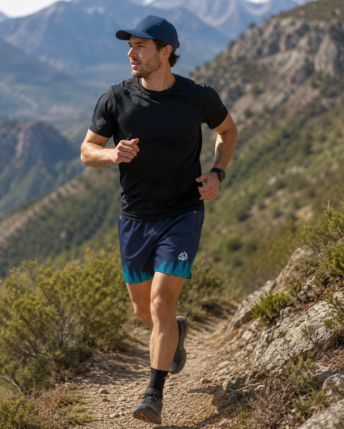 A man trail running on a mountain path wearing a black athletic t-shirt, navy blue shorts with a teal gradient hem, and a navy blue baseball cap.